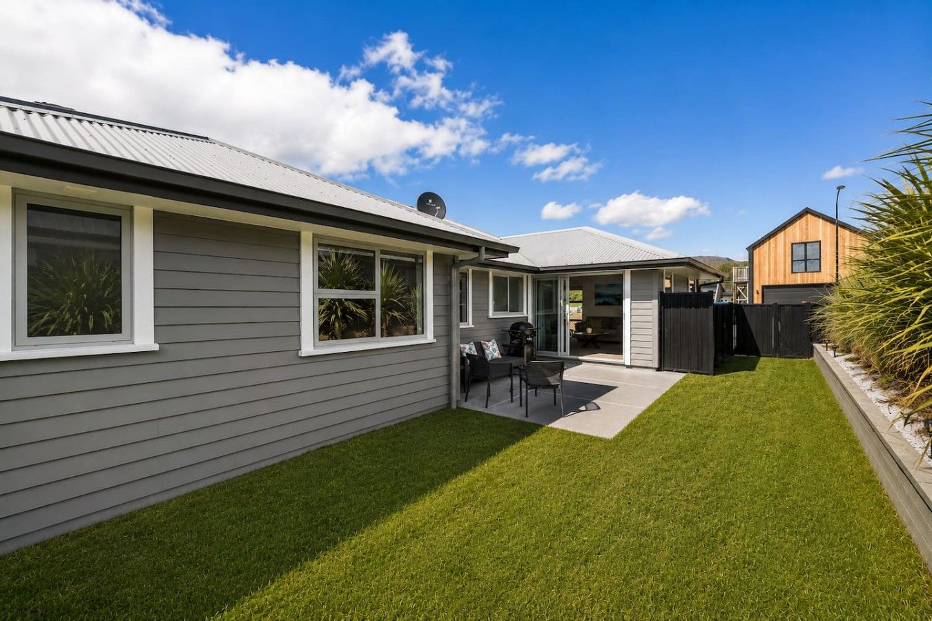 A residential property with a well-maintained lawn, a patio with outdoor furniture, and a garage.