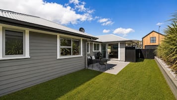A residential property with a well-maintained lawn, a patio with outdoor furniture, and a garage.