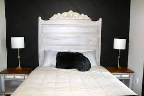 A bed with a white headboard, two bedside lamps, and a black decorative pillow.
