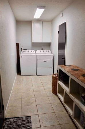 A laundry room with two stacked washers and dryers, a tiled floor, and a cabinet above the dryers.