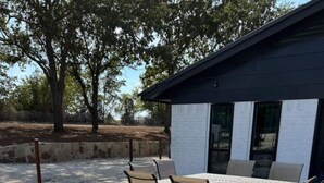 Una veranda esterna con pavimento in pietra, un tavolo rotondo e sei sedie.