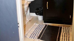 Un bagno con il water, un mobiletti nero, un lavandino e uno specchio.