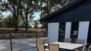An outdoor patio with a stone floor, a metal fire pit, and a table with chairs. - 1BR Ranch Studio | Winery Escapes & Scenic Countryside Views (Saint Jo)