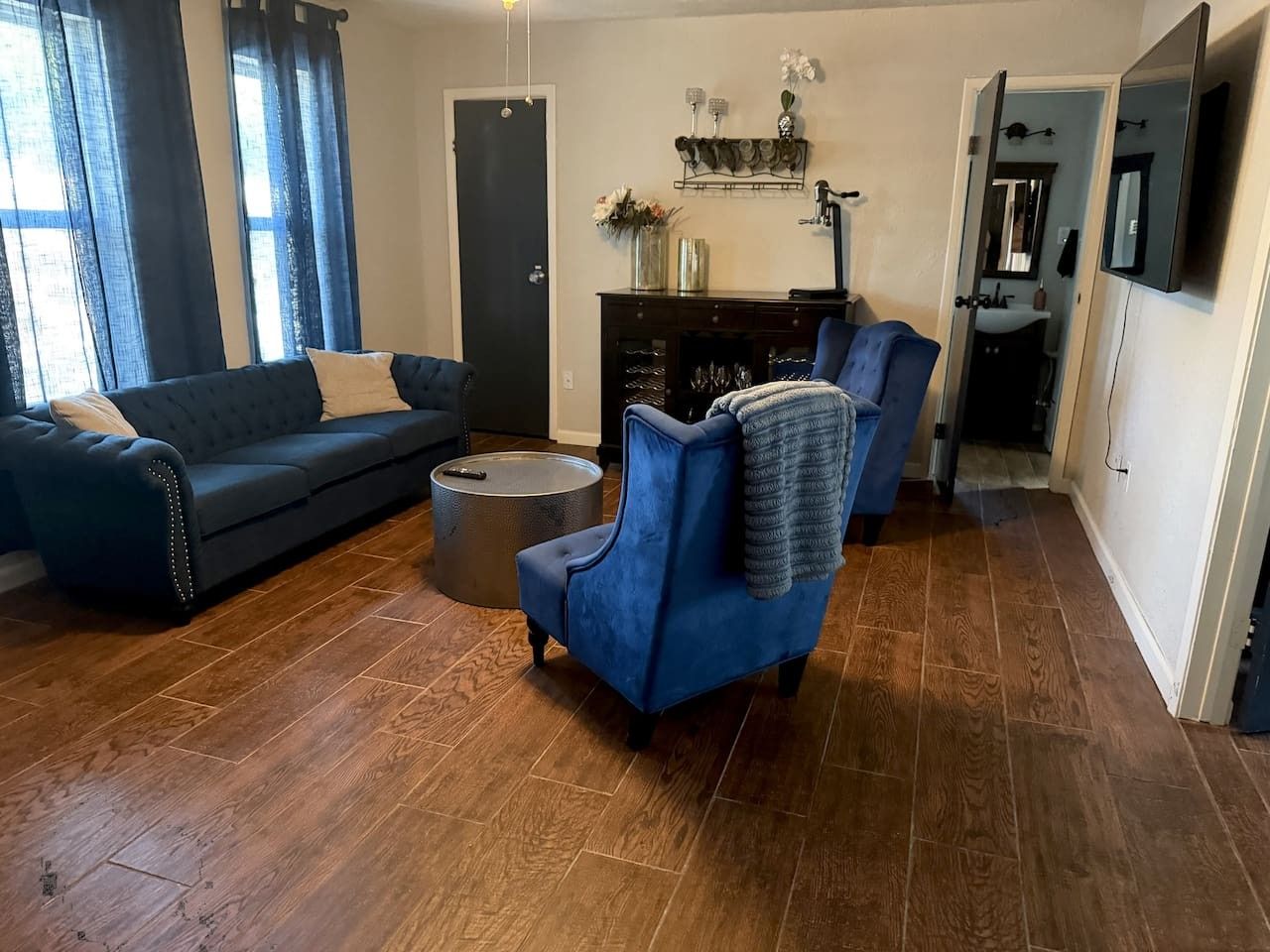 Ein Wohnzimmer mit blauem Sofa, blauem Sessel, einem runden Couchtisch und einem Kamin.