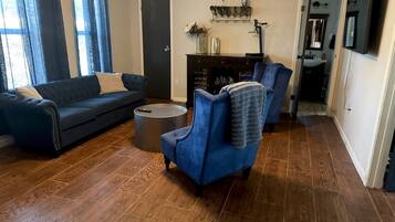 Ein Wohnzimmer mit blauem Sofa, blauem Sessel, einem runden Couchtisch und einem Kamin.