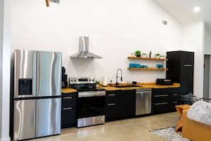 Una cocina moderna con electrodomésticos de acero inoxidable, muebles de color negro y encimeras de madera.