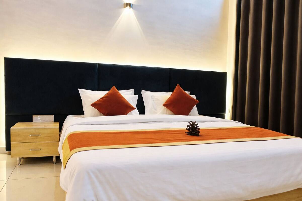 A hotel room with a bed, a nightstand, and a wall-mounted light.