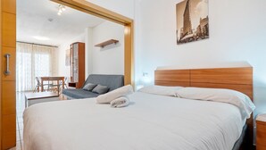 Quarto de hotel com cama, escrivaninha, cadeira, guarda-roupa e espelho.