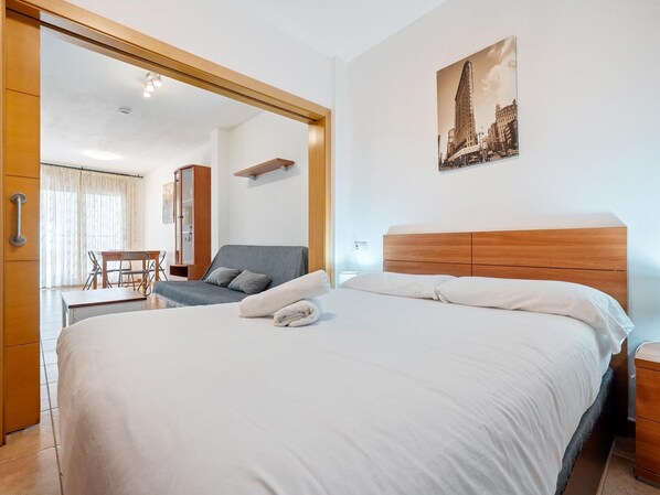 Hotellihuone, jossa on sänky, työpöytä, tuoli, vaatekaappi ja peili.