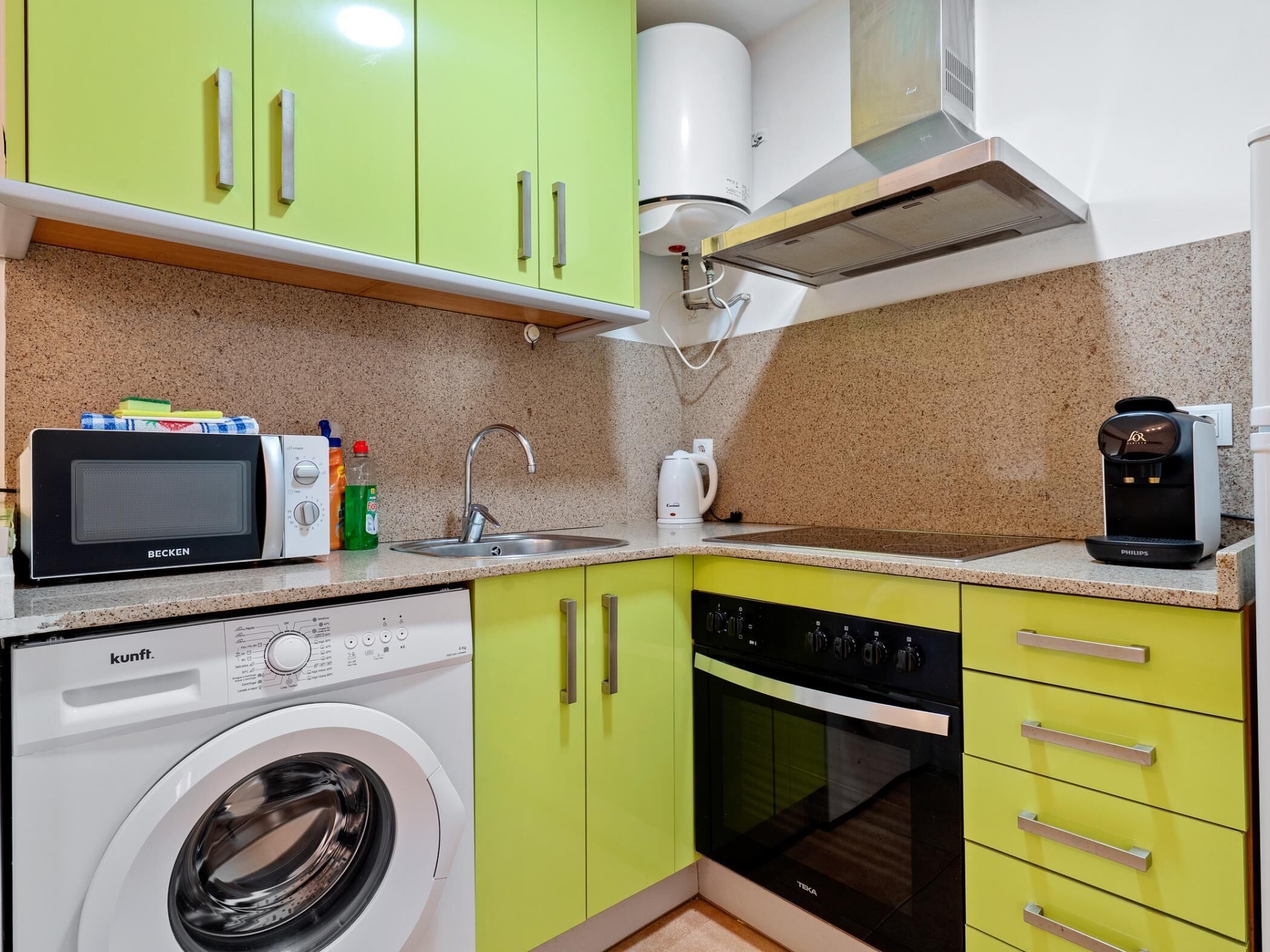 Une cuisine compacte équipée d’un lave-linge, d’un four à micro-ondes, d’un évier et d’une machine à café.