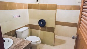 A small bathroom with a toilet, sink, and a paper towel dispenser.
