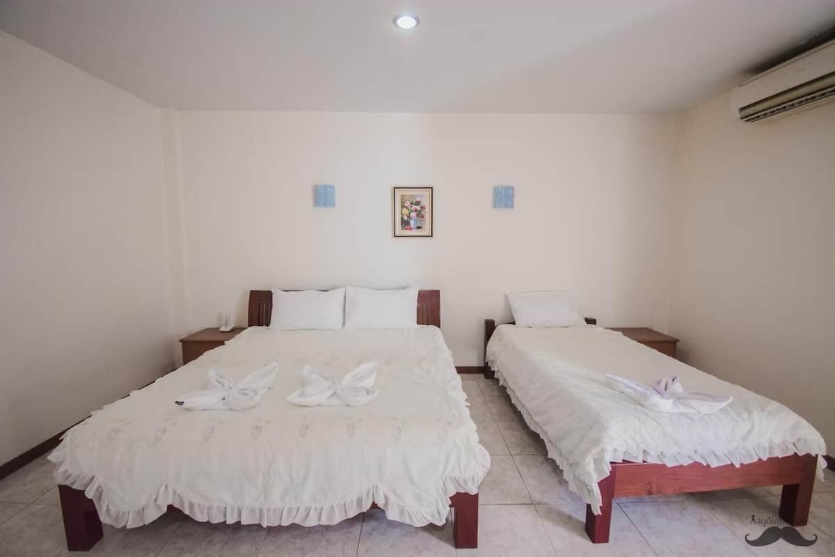 A hotel room with two beds, each with a white bedspread and towels arranged in a swan shape.