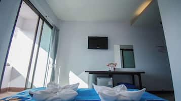 A hotel room with a bed, a desk, a television, and a large window.
