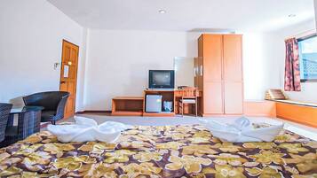 A hotel room with a bed, a desk, a television, and a wardrobe.