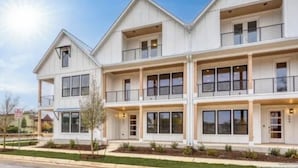 A multi-story residential building with a symmetrical facade, large windows, and a central entrance.