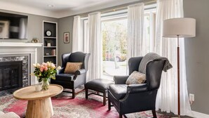 Ein Wohnzimmer mit Kamin, zwei Ledersessel, einem Couchtisch und einer Stehlampe.