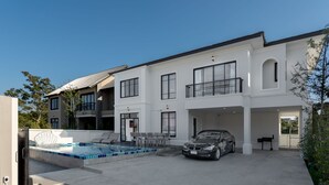 Une maison moderne à deux étages, dotée d’une piscine, d’un garage fermé et d’une voiture garée devant.
