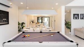 Un salon moderne comprenant une table de billard, un coin repas et un canapé.