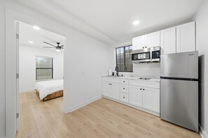 A modern kitchen with white cabinets, a stainless steel refrigerator, and a built-in microwave. - Two historic homes for one price near Downtown and the River Walk (San Antonio)