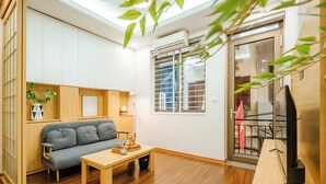 A modern living room with a grey sofa, wooden coffee table, and a TV stand. - The Setai Apartments Linh Lang by XÔI Residences (Hanoi)
