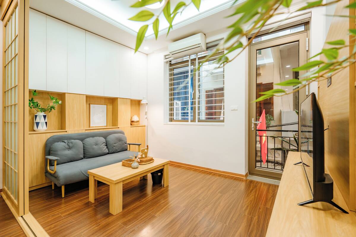 Una sala moderna con un sofá gris, una mesa de centro de madera y un mueble para televisión.