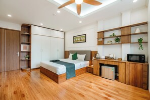 Une chambre moderne comprenant un lit, une armoire en bois, des étagères intégrées, un four à micro-ondes et un petit réfrigérateur.