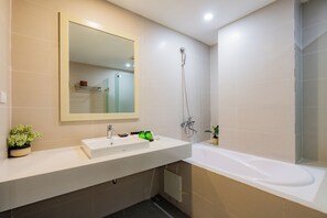 Une salle de bain moderne avec un lavabo blanc, un grand miroir, une douche et une baignoire.