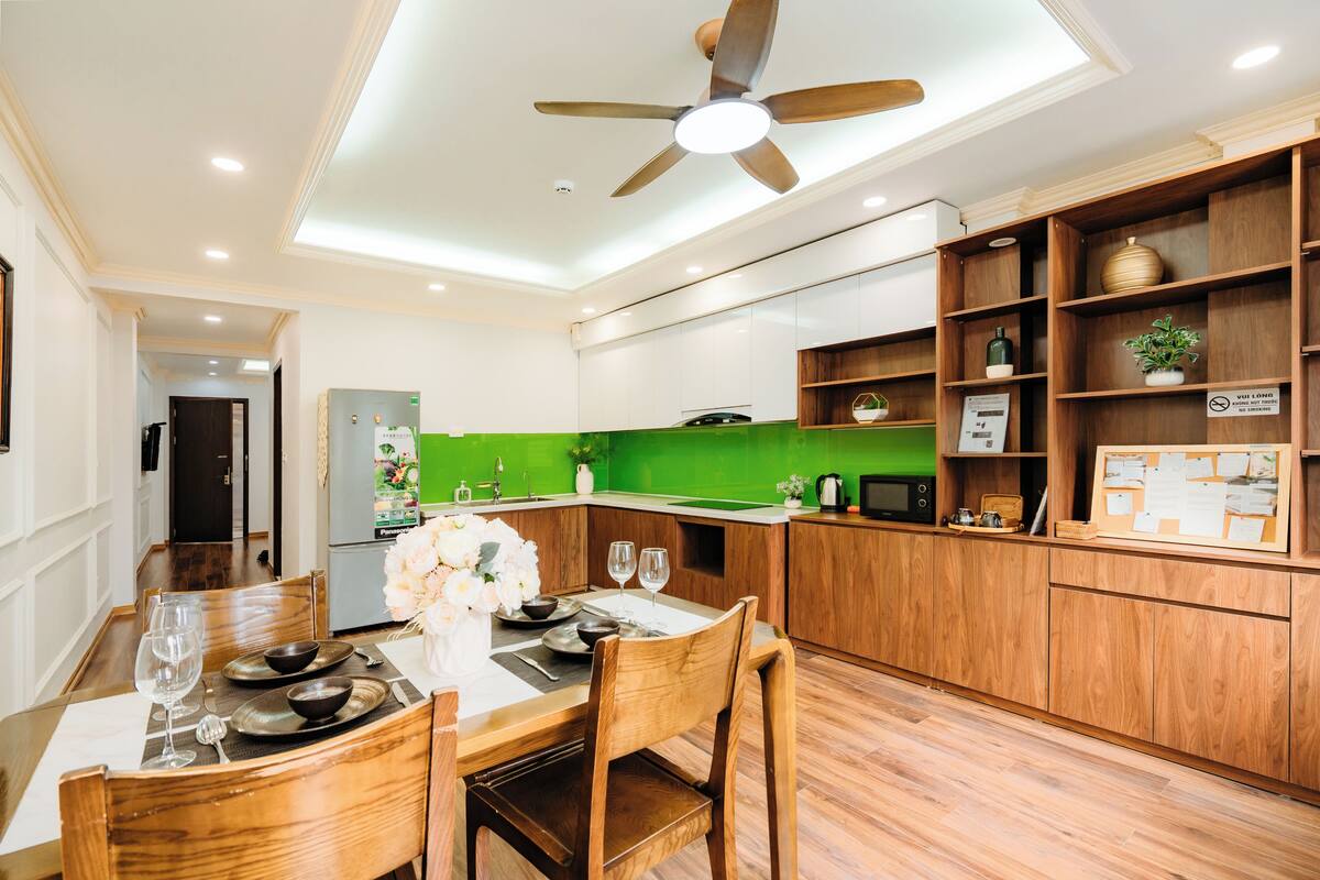 Una cocina moderna con armarios de madera, una mesa de comedor para dos personas y un ventilador de techo.