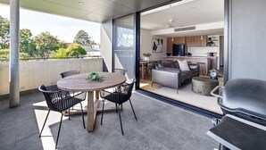 A modern apartment with a balcony, a dining area, and a kitchen visible through a glass door. - Margaret's Luxe Apartment (Margaret River)