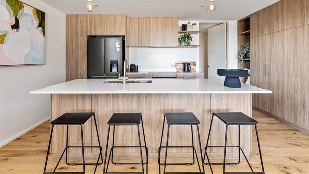 A modern kitchen with a central island, stainless steel appliances, wooden cabinets, and bar stools. - Margaret's Luxe Apartment (Margaret River)