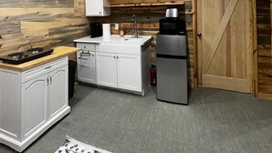 Una cocina compacta con paneles de madera, armarios blancos, un refrigerador de acero inoxidable y una estufa empotrada.