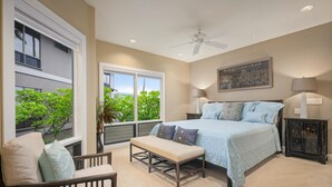 A bedroom with a bed, bench, chair, and a ceiling fan.