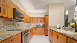 A modern kitchen with wooden cabinets, a microwave, a coffee maker, and a sink.