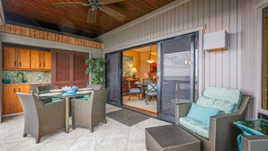 Eine Terrasse im Freien mit Korbmöbeln, einem Deckenventilator und Blick ins Haus.
