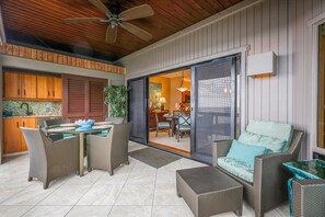 Eine Terrasse im Freien mit Korbmöbeln, einem Deckenventilator und Blick ins Haus.