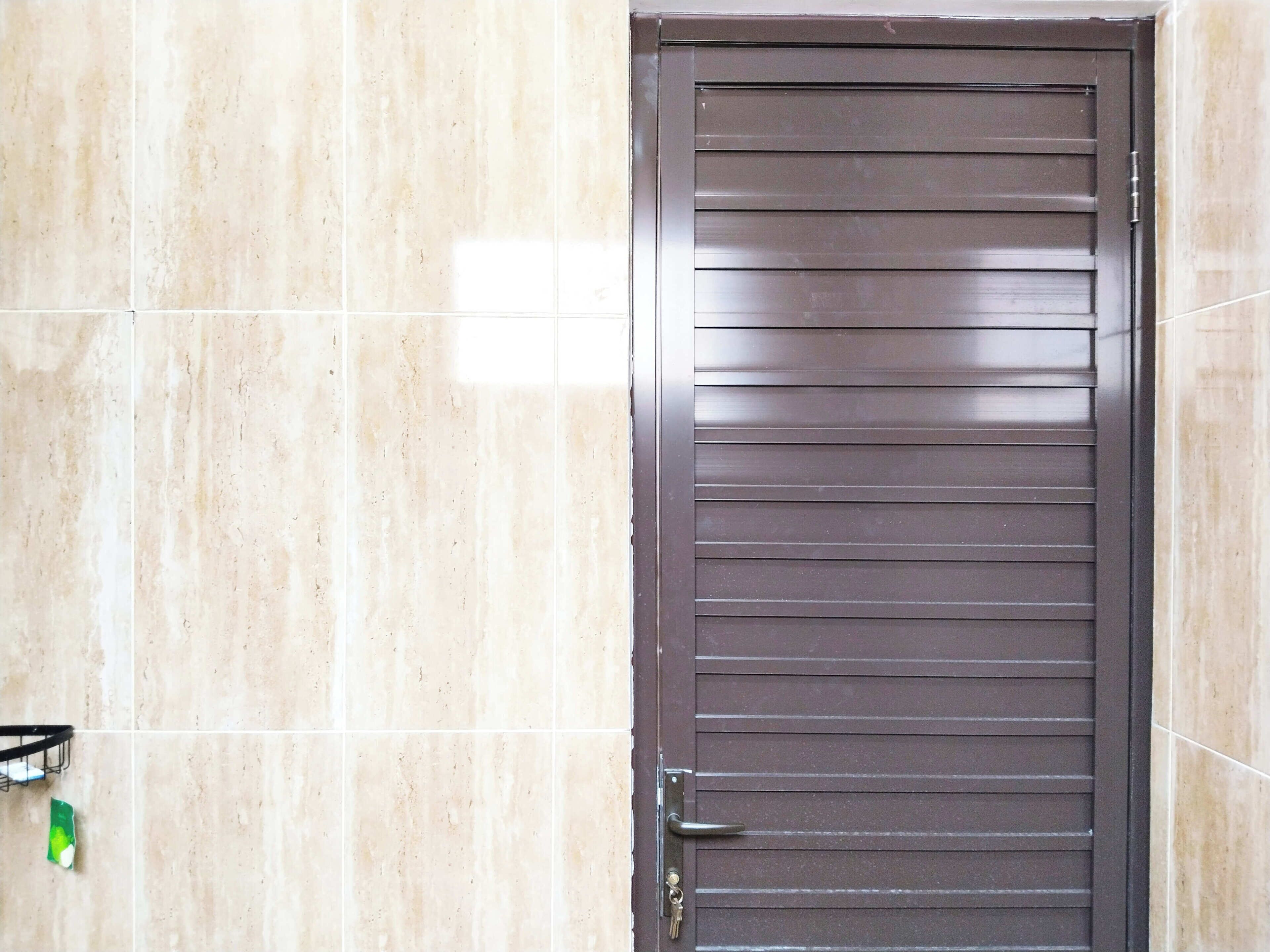 Puerta metálica cerrada con listones horizontales y cerradura con agujero para llave.