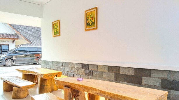 Un espace extérieur moderne, aménagé avec des bancs et des tables en bois, un mur en pierre et deux œuvres d’art encadrées accrochées au mur.