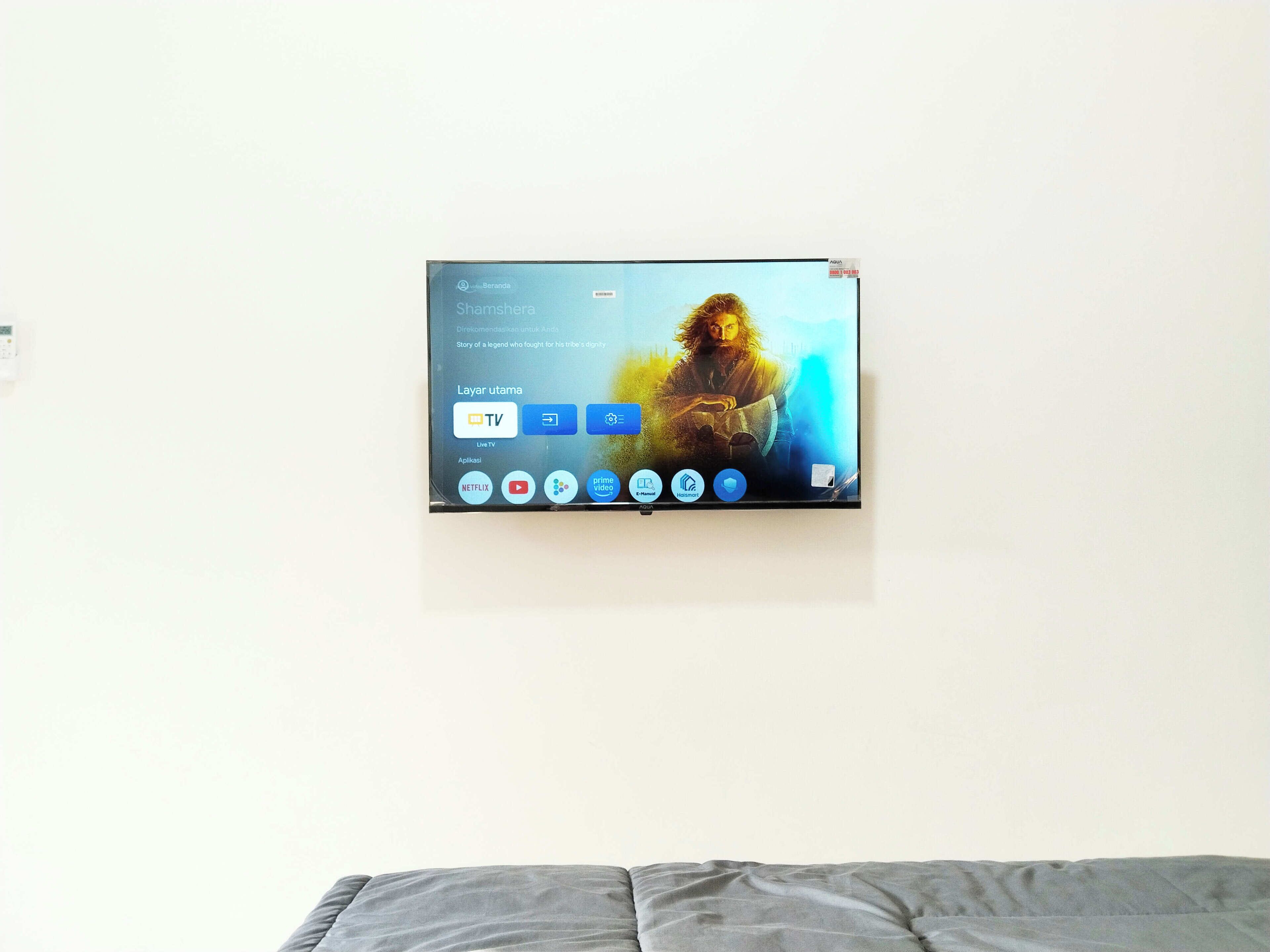 A flat-screen TV mounted on a white wall displaying a movie with a TV icon and a Netflix logo.