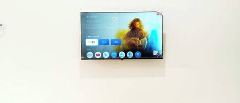 A flat-screen TV mounted on a white wall displaying a movie with a TV icon and a Netflix logo.