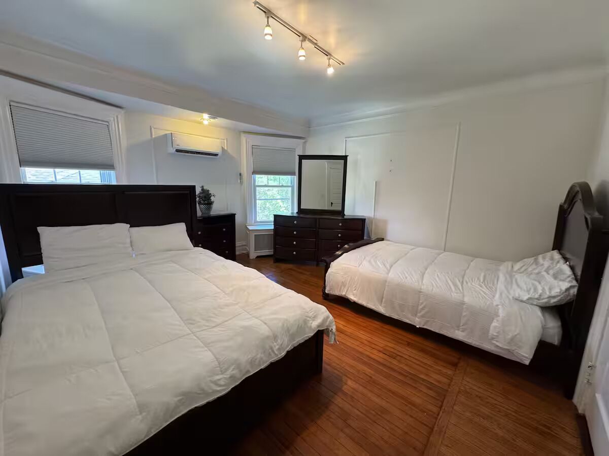 Una camera da letto con due letti, una cassettiera e uno specchio.