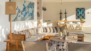 A spacious living area with a high ceiling, a large sofa set, a dining table, and a ceiling fan. - Balidroomvillas (Karangasem)