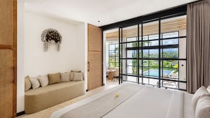 A modern hotel room with a large bed, a sofa, a view of a pool, and a balcony. - Balidroomvillas (Karangasem)