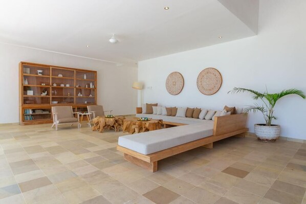 A modern living room with a wooden sofa, a wooden coffee table, and a bookshelf. - Balidroomvillas (Karangasem)