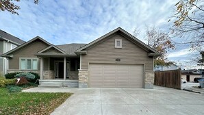 A two-story house with a garage, a stone foundation, and a well-maintained front yard. - Walk to Grand Bend Main Beach | Sleeps 8 | Family Friendly | Heart of Grand Bend (Grand Bend)
