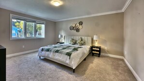 A bedroom with a large bed, two bedside tables, a window, and a ceiling light. - Walk to Grand Bend Main Beach | Sleeps 8 | Family Friendly | Heart of Grand Bend (Grand Bend)