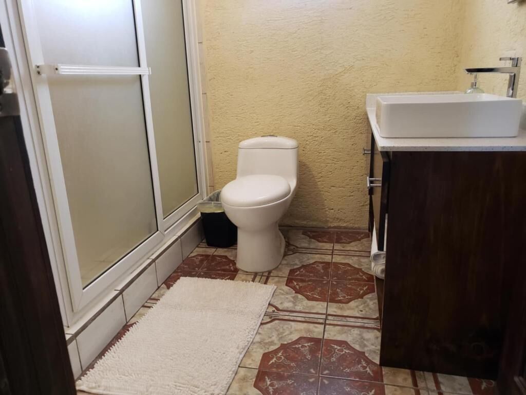A bathroom with a toilet, sink, and shower area.