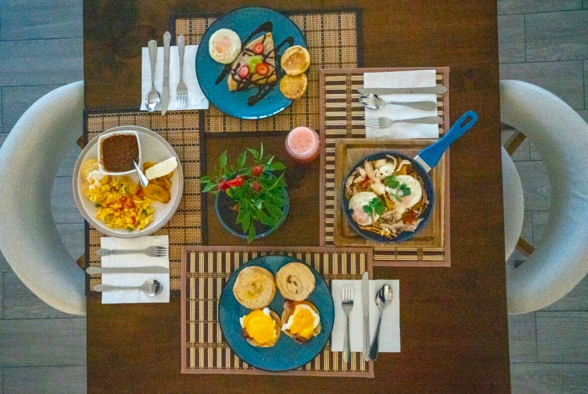 Una mesa de comedor con diferentes platos, cubiertos y un mantel individual.