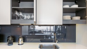 A modern kitchen with a stainless steel sink, a built-in stove, and a view of the cityscape through large windows. - Blueground | DIFC, pool, nr Dubai Fountain (Dubai)