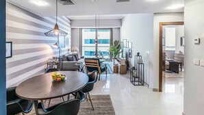 Ein modernes Wohnzimmer mit Essbereich, großen Fenstern und Blick auf die Stadt.