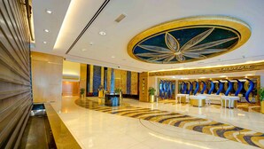 Eine großzügige Lobby mit einer zentralen Rezeption, einer gebogenen Sitzgruppe und einer dekorativen Decke.